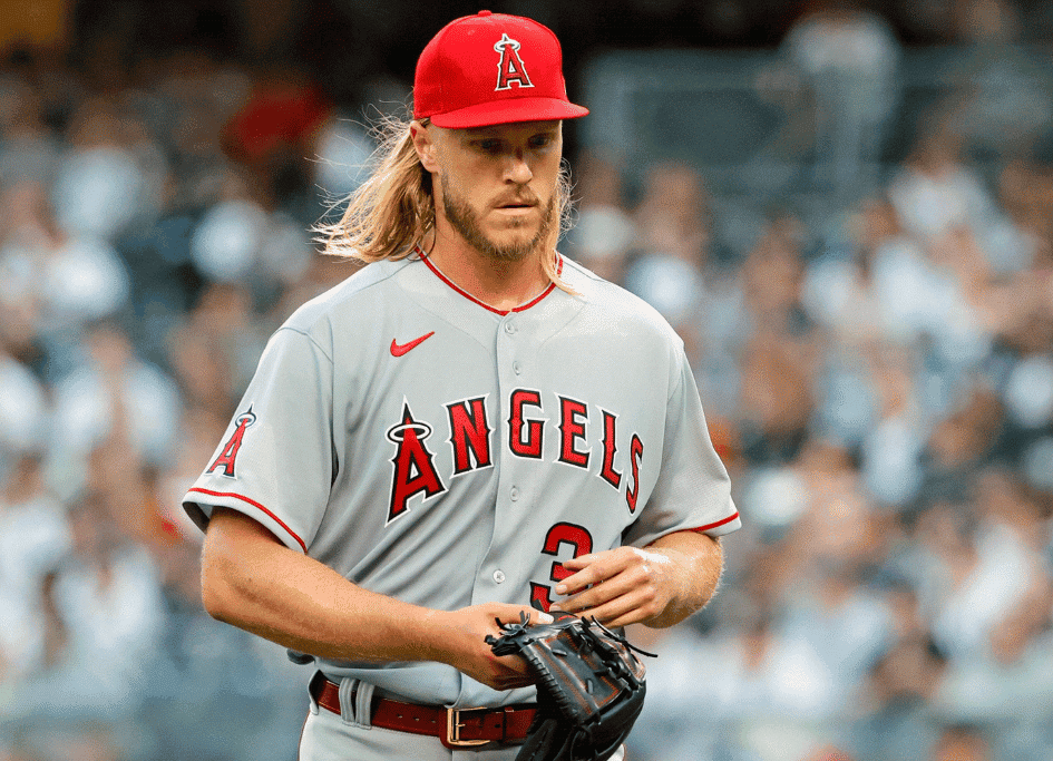 Baseball player in a gray Angels uniform and red cap, casually walking on the field with a glove in hand, as if he's just stepped out of the red light therapy community. The crowd buzzes in the background.