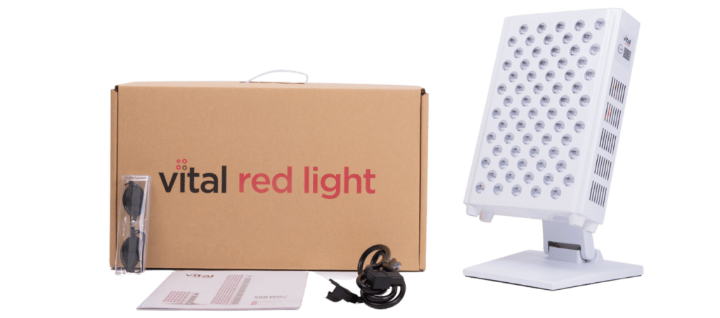 Red light therapy device with stand, goggles, user manual, and power cord sits next to a cardboard box labeled "Vital Red Light," ideal for wholesale buyers.