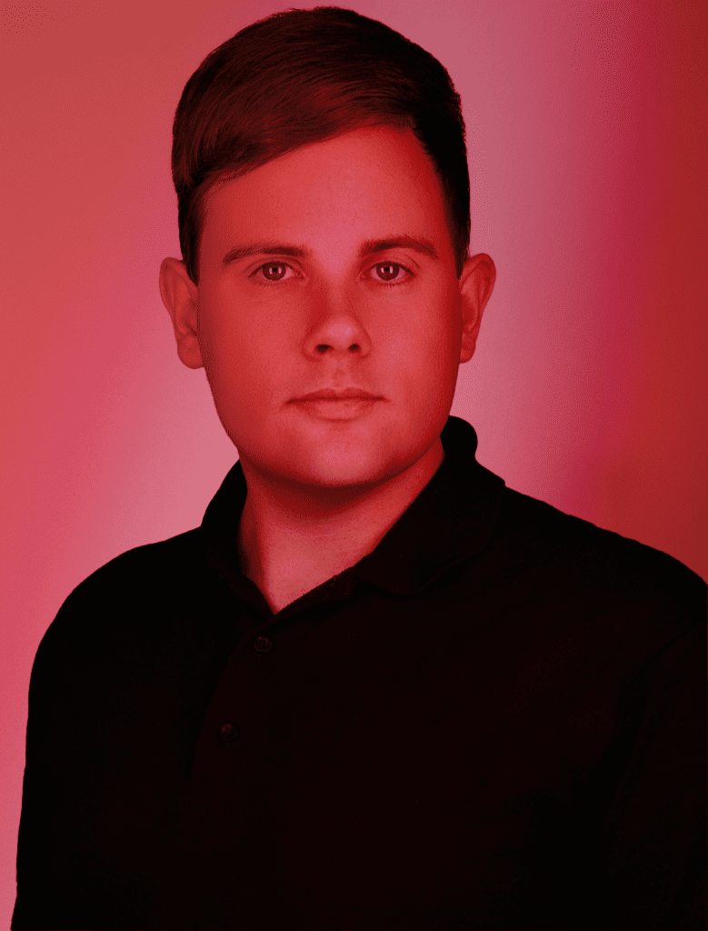 Standing confidently in a black shirt, this short-haired individual embodies the spirit of "About Us," set against a striking red-tinted background.